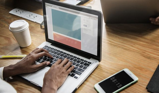 Adult typing on a computer with coffee nearby