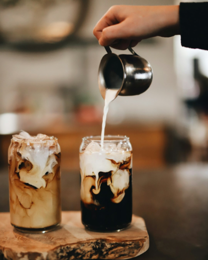 Woman pouring iced coffee in a glass on a wooden block